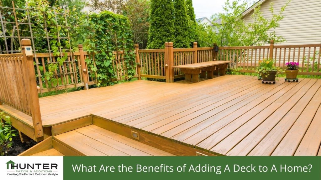 FAQs about Decking in Newcastle - Deck Wooden deck with greenery and bench seating.